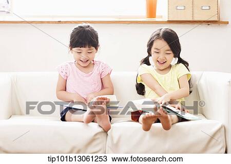 Stock Image - two girls reading a book. Fotosearch