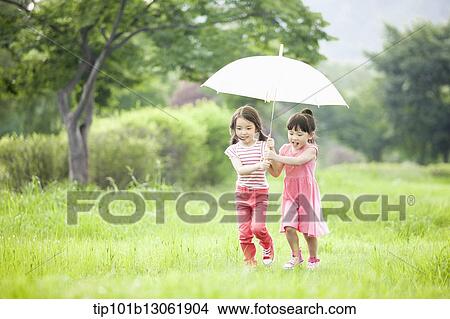 two girls walking with an umbrella View Large Photo Image Picture - two girls walking with an umbrella. Fotosearch