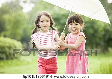 Picture - two girls walking with an umbrella. Fotosearch