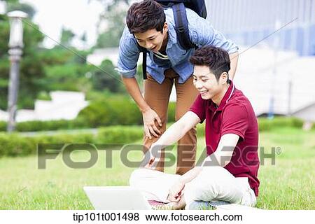 Stock Photo - two man on grass looking at laptop together. Fotosearch
