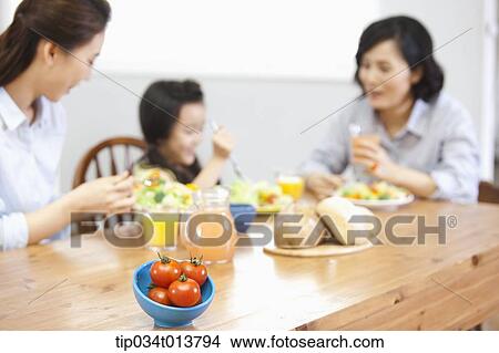 Picture - two women and a kid in the kitchen. Fotosearch