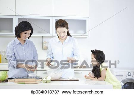 Stock Photo - two women cooking in the kitchen while a child watching. Fotosearch