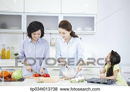 Stock Photo - two women cooking in the kitchen while a child watching. Fotosearch