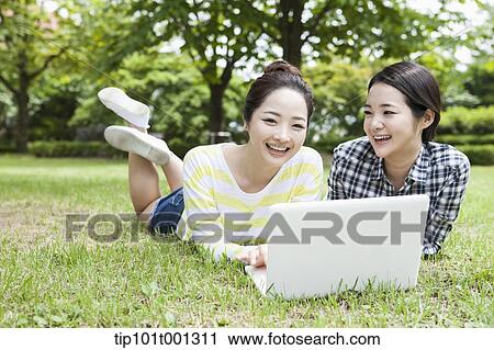 university students lying on grass working with a laptop View Large Photo Image Stock Image - university students lying on grass working with a laptop. Fotosearch