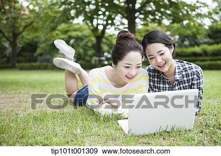 university students lying on grass working with a laptop View Large Photo Image Stock Photo - university students lying on grass working with a laptop. Fotosearch