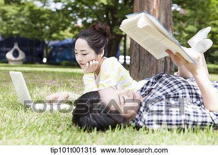 Stock Photography - university students lying on grass working . Fotosearch