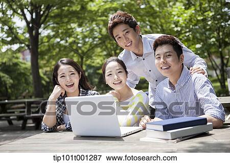 Stock Photo - university students working together with a laptop at wooden out door table . Fotosearch