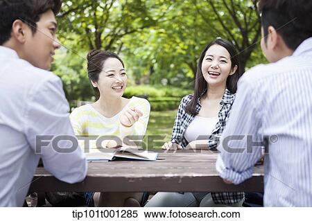 Stock Photography - university students working together sitting at wooden out door table . Fotosearch