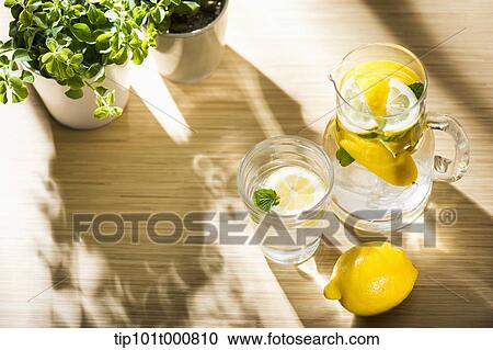 Stock Image - water pot and water glass with lemon inside. Fotosearch