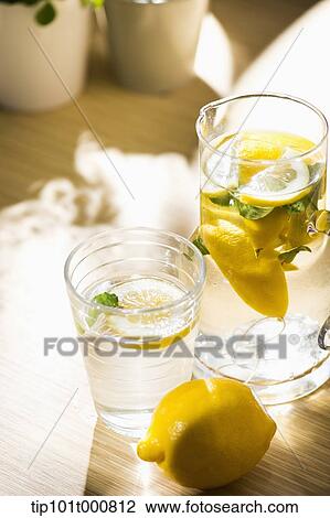 Stock Image - water pot and water glass with lemon inside. Fotosearch