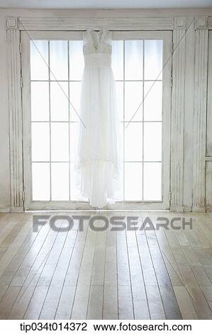 Stock Image - wedding dress hanging in bride's room. Fotosearch