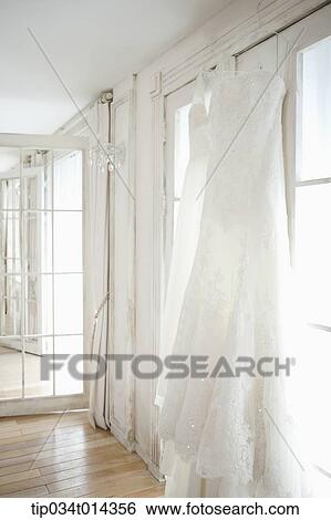 Stock Photograph - wedding dress hanging in bride's room. Fotosearch
