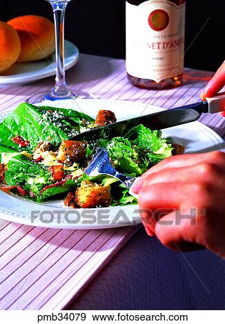 Stock Photo - knife, salad, western dish, western food, hand, Caesar salad. Fotosearch