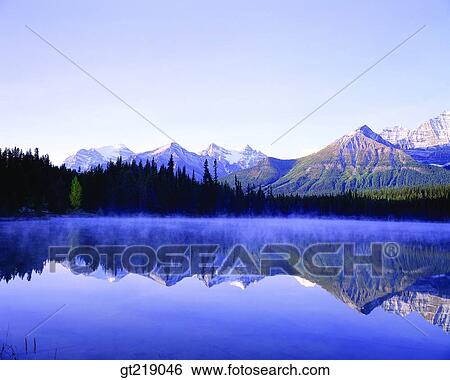 Stock Photograph - lake, mountain, forest, trees, remaining snow, reflection, reflect. Fotosearch