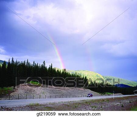 Stock Photo - rainbow, mountain, forest, trees, street, road, car. Fotosearch