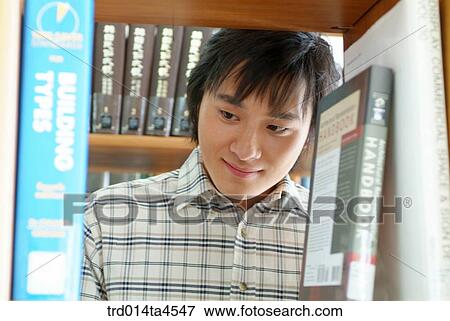 A boy looking for a book in the library View Large Photo Image Stock Photo - A boy looking for a book in the library. Fotosearch