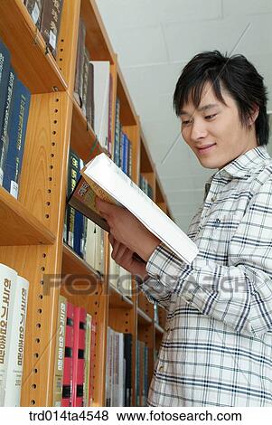 Stock Photo - A boy looking for a book in the library. Fotosearch