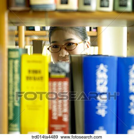 Stock Photo - A woman looking for a book. Fotosearch
