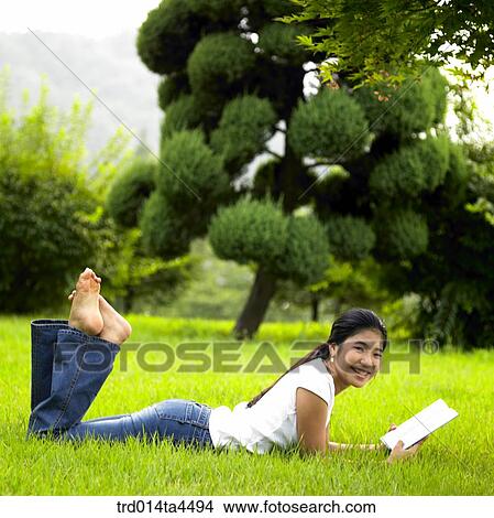 a woman reading a book on the grass View Large Photo Image Picture - a woman reading a book on the grass. Fotosearch