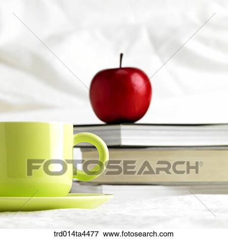 An apple and a cup on the book View Large Photo Image Stock Photo - An apple and a cup on the book. Fotosearch