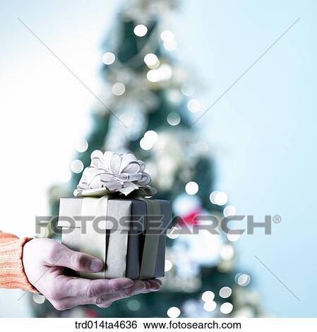 Stock Photograph - A hand holding a Christmas gift. Fotosearch
