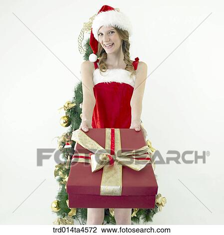 Stock Image - a woman wearing Santa Claus' clothes and giving gifts. Fotosearch