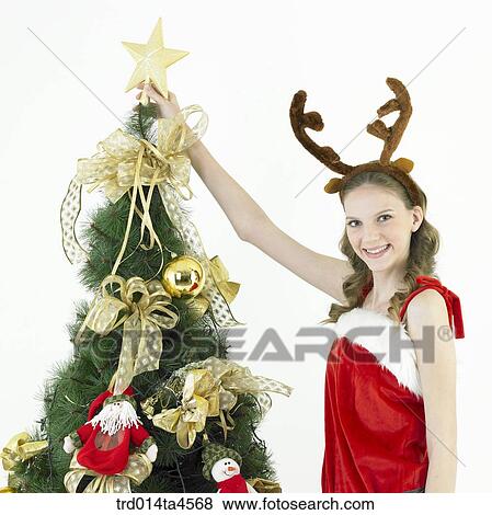 Stock Photo - Christmas Tree, a woman wearing Santa Claus' clothes. Fotosearch