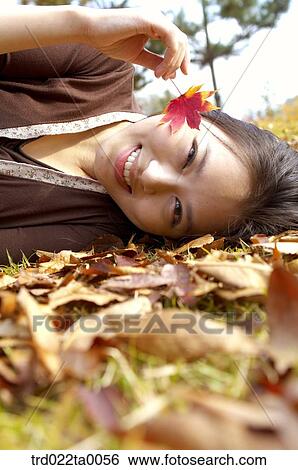 A lying woman holding a maple leaf View Large Photo Image Stock Photograph - A lying woman holding a maple leaf. Fotosearch