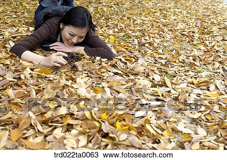 Stock Image - A lying woman looking at pine cone. Fotosearch
