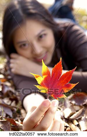 A procumbent woman holding a maple leaf View Large Photo Image Stock Photo - A procumbent woman holding a maple leaf. Fotosearch