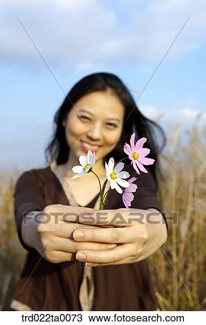 Stock Image - A woman holding a cosmos. Fotosearch