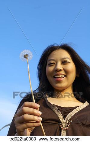 Stock Image - A woman holding a dandelion. Fotosearch
