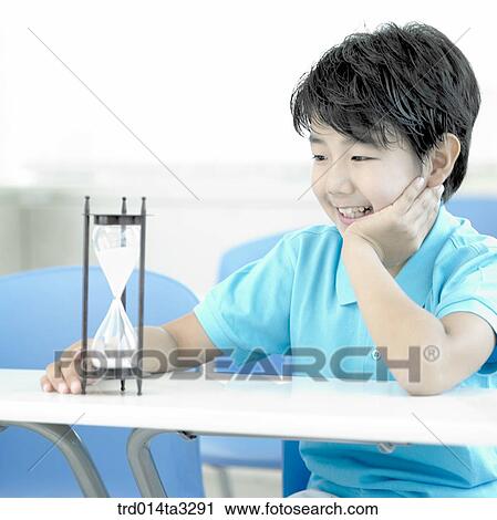 Stock Image - Boy looking at sandglass. Fotosearch