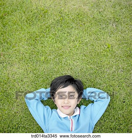 Stock Photography - Boy lying down in the lawn. Fotosearch