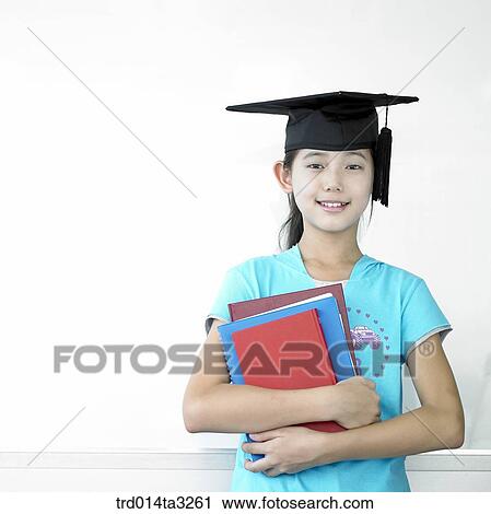 Stock Image - Child, Boy wearing graduation cap and hloing books. Fotosearch