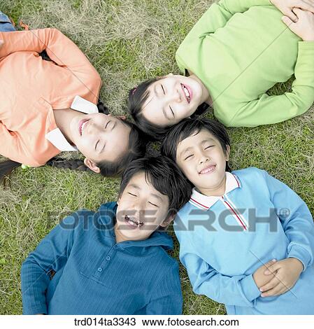 Stock Image - Children lying down in the lawn. Fotosearch