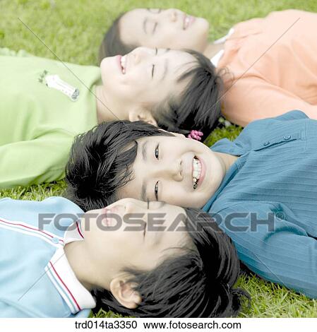 Stock Image - Children lying down in the lawn. Fotosearch