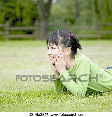 Stock Photo - Girl lying prone at the lawn. Fotosearch