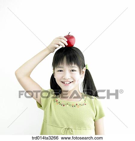 Stock Photograph - Girl putting apple on her head. Fotosearch