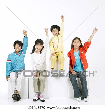 Stock Image - Children raising hands and sitting in a row. Fotosearch