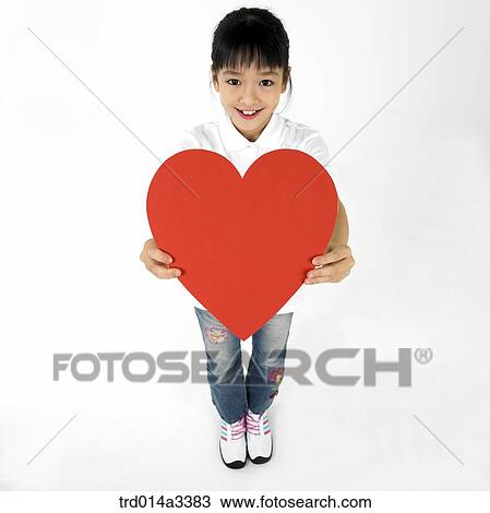 Stock Image - girl holding heart shaped balloon over her head. Fotosearch