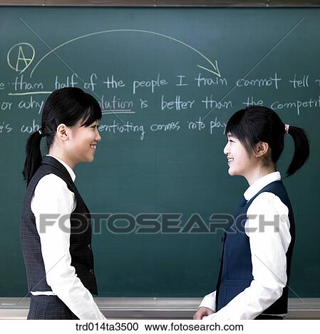 Two girsl in class facing each other in front of blackboard View Large Photo Image Stock Image - Two girsl in class facing each other in front of blackboard. Fotosearch