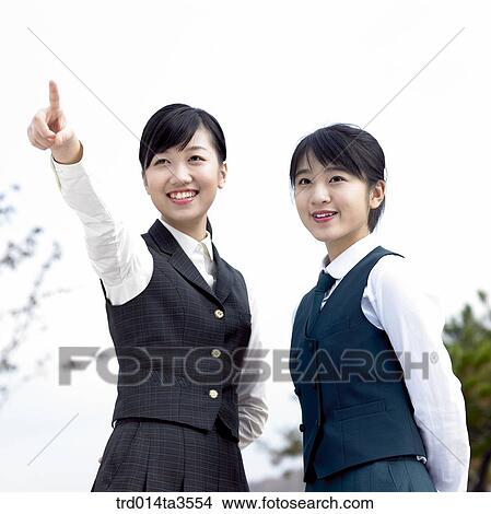 Picture - Two standing students in uniform pointing at. Fotosearch