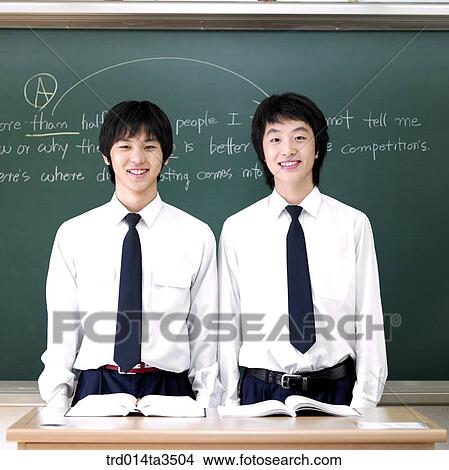 two students standing in front of the blackboard in the classroom View Large Photo Image Picture - two students standing in front of the blackboard in the classroom. Fotosearch