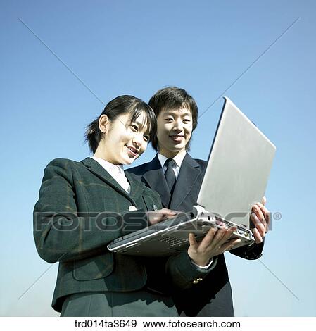 Teen in unifrom looking at notebook computer View Large Photo Image Stock Photo - Teen in unifrom looking at notebook computer. Fotosearch