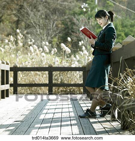 Teen leanning against fence andreading book at outside View Large Photo Image Stock Photo - Teen leanning against fence andreading book at outside. Fotosearch