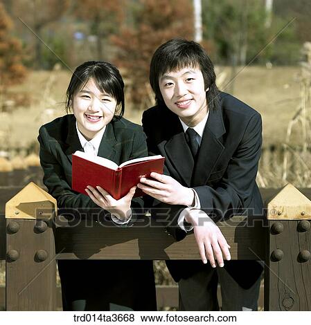 Teens holding books and leanning against fence View Large Photo Image Stock Photo - Teens holding books and leanning against fence. Fotosearch