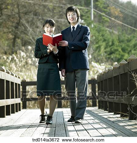 Teens holding books while walking the bridge View Large Photo Image Stock Image - Teens holding books while walking the bridge. Fotosearch
