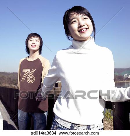 Picture - Teens holding hands near the fence. Fotosearch
