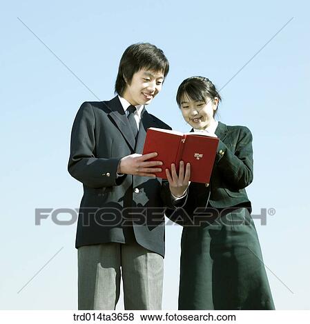 Teens in uniform reading books together View Large Photo Image Stock Photo - Teens in uniform reading books together . Fotosearch